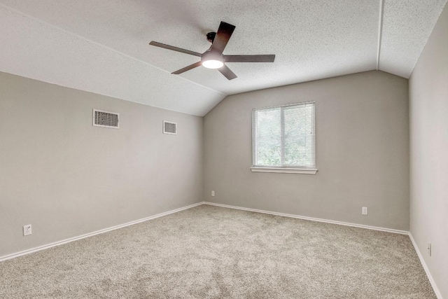 interior space with a ceiling fan, a textured ceiling, visible vents, vaulted ceiling, and baseboards