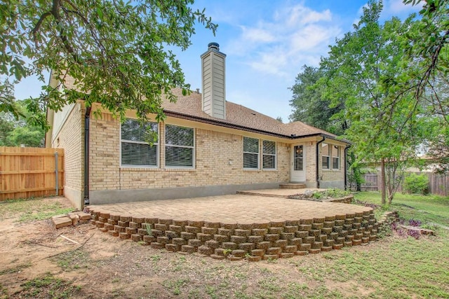 rear view of house featuring brick siding, a patio, a chimney, and a fenced backyard