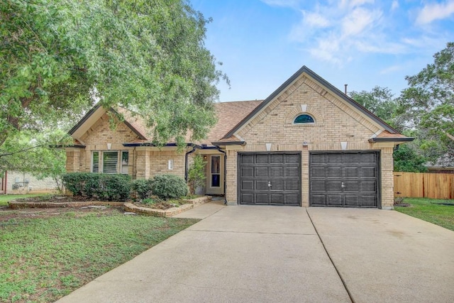 view of front facade with fence, an attached garage, brick siding, a front yard, and driveway