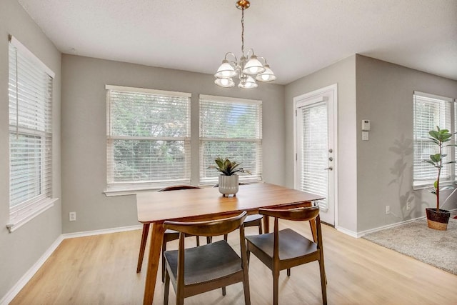 dining area with an inviting chandelier, light wood-style floors, plenty of natural light, and baseboards