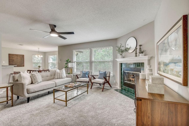 living room with carpet flooring, a textured ceiling, a tiled fireplace, and ceiling fan with notable chandelier