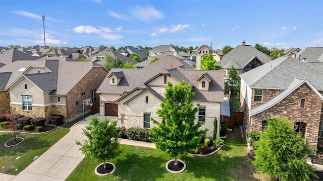 view of front facade with a front lawn, stone siding, concrete driveway, an attached garage, and a residential view