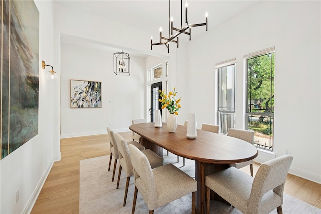201 Explorer, Lakeway, TX 78734 - dining area featuring a chandelier, light wood-style flooring, baseboards, and a towering ceiling