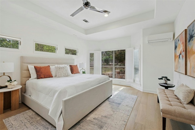 201 Explorer, Lakeway, TX 78734 - bedroom featuring a wall mounted AC, light wood-type flooring, a tray ceiling, baseboards, and a ceiling fan