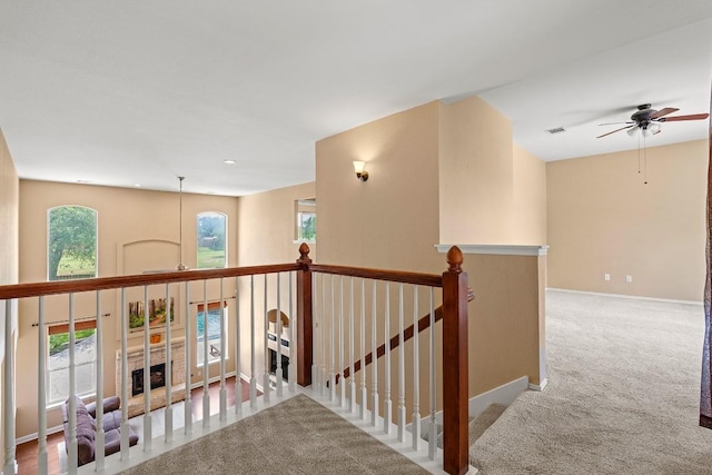 corridor featuring carpet floors, visible vents, baseboards, and an upstairs landing