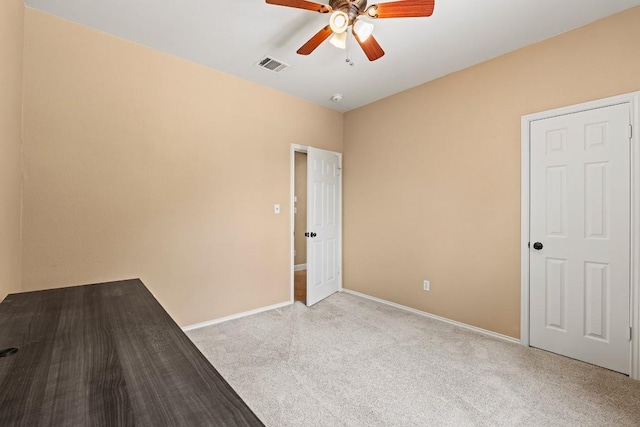 empty room with carpet floors, ceiling fan, baseboards, and visible vents
