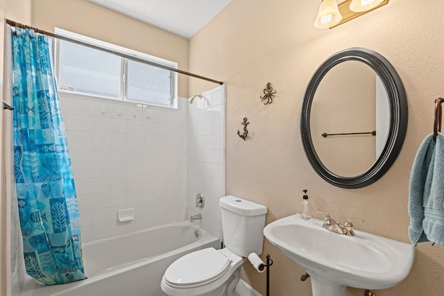 full bath featuring a sink, a textured wall, shower / bath combo with shower curtain, and toilet