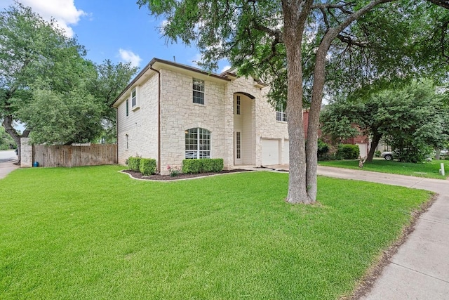 traditional-style house with a garage, fence, a front lawn, concrete driveway, and stone siding