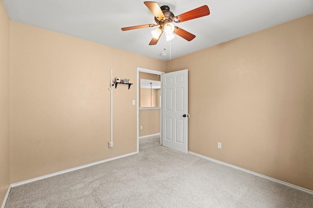 empty room with baseboards, ceiling fan, and light colored carpet