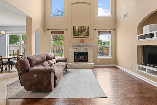 living room featuring a towering ceiling, visible vents, built in features, and a fireplace