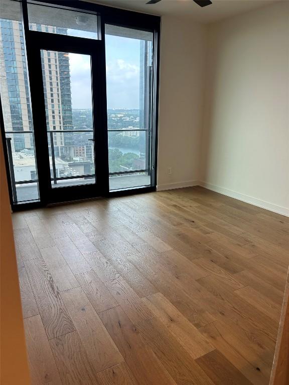 84 E Ave Unit 2207, Austin, TX 78701 - unfurnished room featuring baseboards, a ceiling fan, expansive windows, and wood finished floors