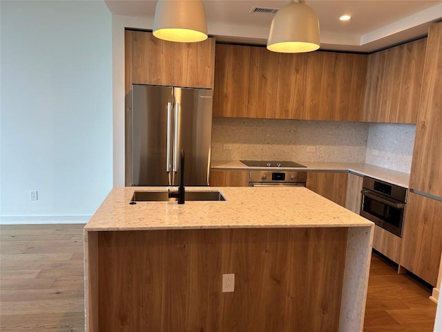 84 E Ave Unit 2207, Austin, TX 78701 - kitchen featuring appliances with stainless steel finishes, a sink, brown cabinetry, visible vents, and modern cabinets