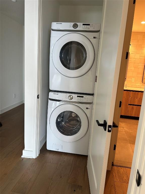 84 E Ave Unit 2207, Austin, TX 78701 - clothes washing area featuring laundry area, baseboards, stacked washer and clothes dryer, and wood finished floors