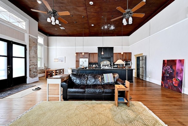 living room featuring wood ceiling, ceiling fan, a towering ceiling, and hardwood / wood-style flooring