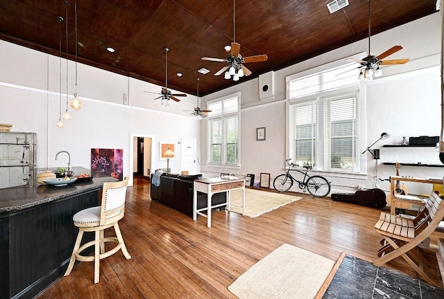 interior space with wood-type flooring, a ceiling fan, visible vents, and wooden ceiling