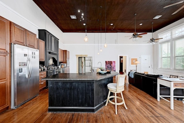 kitchen with a ceiling fan, dark wood-style flooring, dark countertops, stainless steel fridge with ice dispenser, and wooden ceiling
