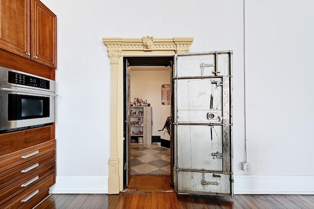 interior space featuring oven, baseboards, dark wood-style floors, and brown cabinetry