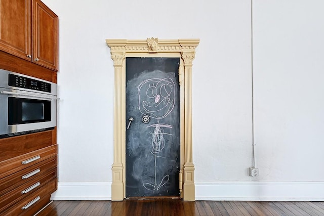 interior details with baseboards, dark wood-style floors, and oven