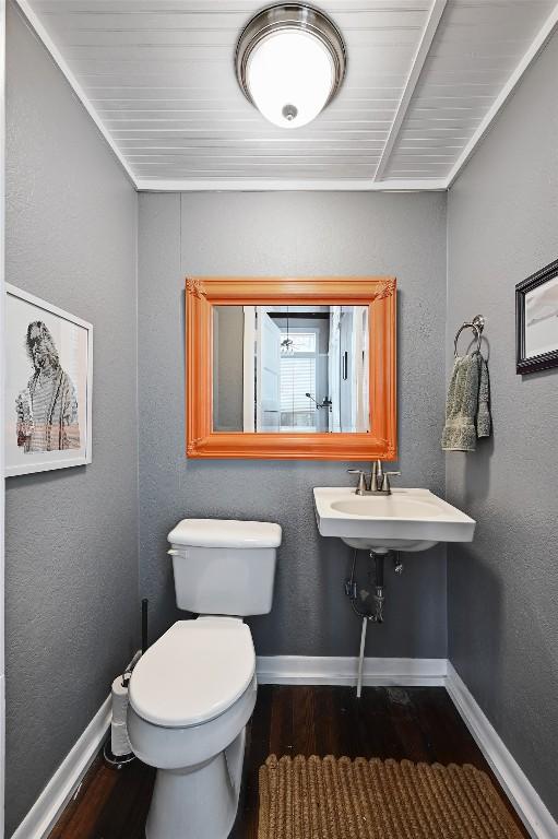 bathroom with baseboards, a sink, wood finished floors, and toilet