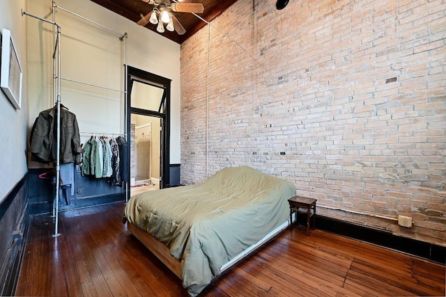 bedroom with brick wall, wooden ceiling, high vaulted ceiling, wood-type flooring, and beamed ceiling