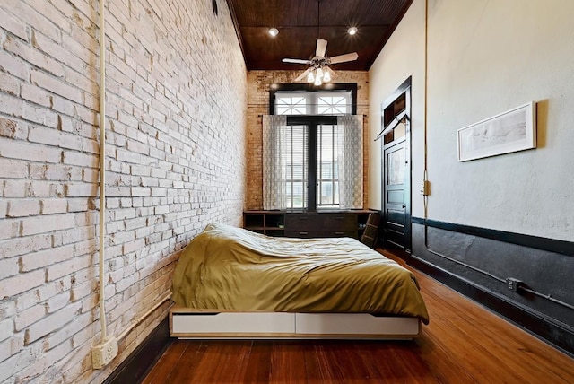 bedroom featuring brick wall, dark wood finished floors, and wood ceiling