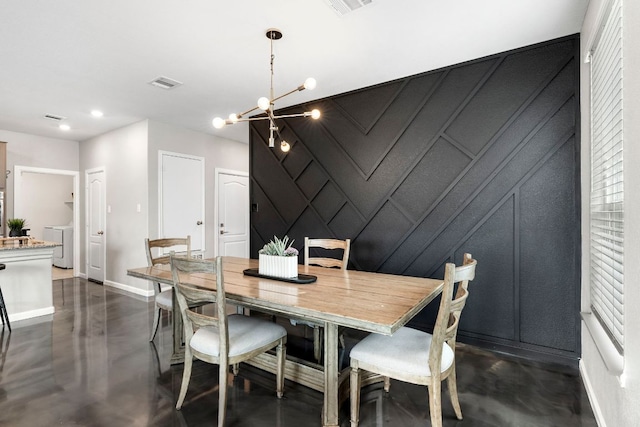 dining space featuring visible vents, an inviting chandelier, finished concrete flooring, a decorative wall, and baseboards