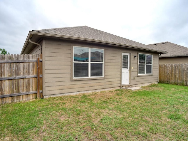 rear view of property with a lawn and a fenced backyard