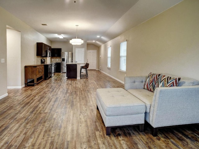 living area featuring baseboards, dark wood finished floors, vaulted ceiling, and visible vents