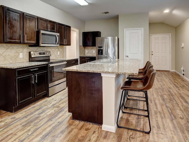 kitchen featuring visible vents, light wood-type flooring, a sink, appliances with stainless steel finishes, and backsplash