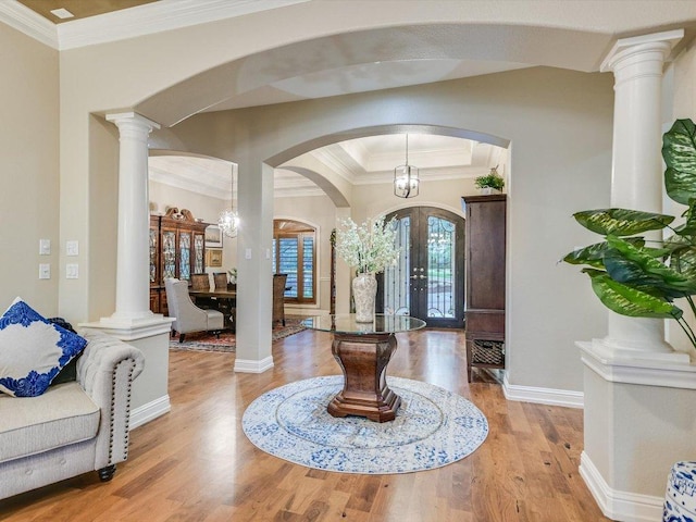 entryway featuring french doors, arched walkways, wood finished floors, baseboards, and ornamental molding