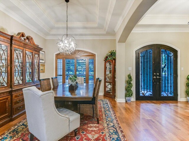 5709 Laguna Cliff Ln, Austin, TX 78734 - dining space featuring arched walkways, a raised ceiling, a chandelier, wood finished floors, and french doors