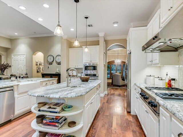 5709 Laguna Cliff Ln, Austin, TX 78734 - kitchen featuring arched walkways, appliances with stainless steel finishes, open shelves, under cabinet range hood, and a kitchen island with sink