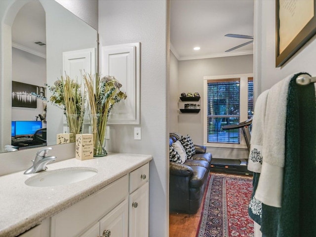 bathroom with crown molding, visible vents, vanity, wood finished floors, and a ceiling fan