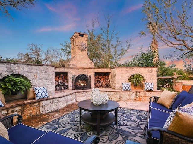 patio terrace at dusk with an outdoor living space with a fireplace