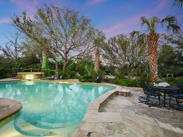 5709 Laguna Cliff Ln, Austin, TX 78734 - pool at dusk featuring an outdoor pool, a patio area, and view of wooded area