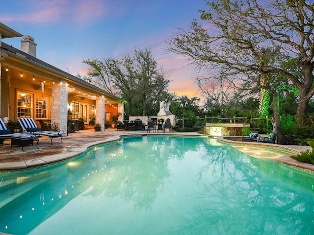 outdoor pool with a patio area and a fireplace