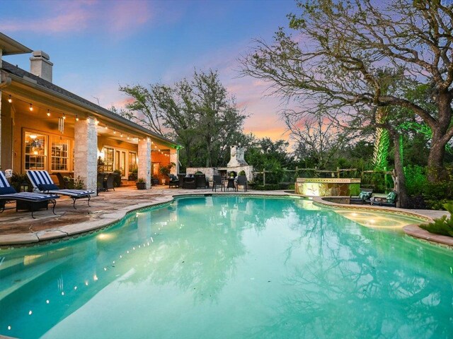 5709 Laguna Cliff Ln, Austin, TX 78734 - pool at dusk with a patio area, a fireplace, and an outdoor pool
