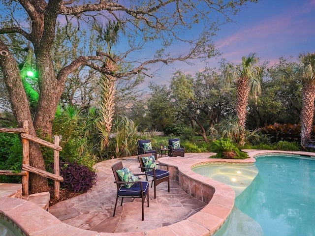 pool at dusk featuring a patio and an outdoor pool