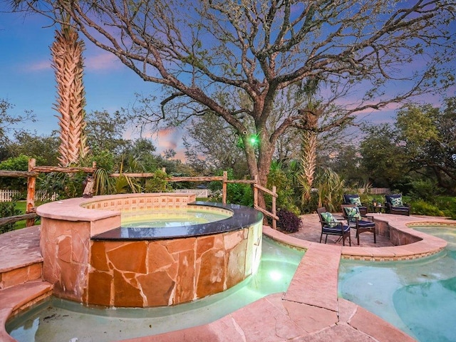 outdoor pool with an in ground hot tub and a patio area