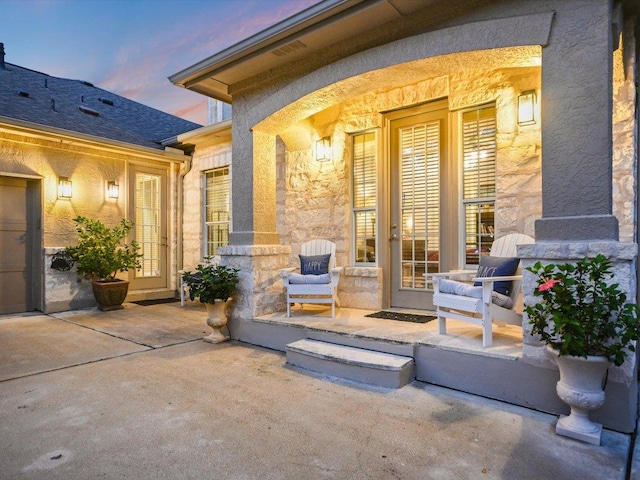 exterior entry at dusk with french doors and stone siding