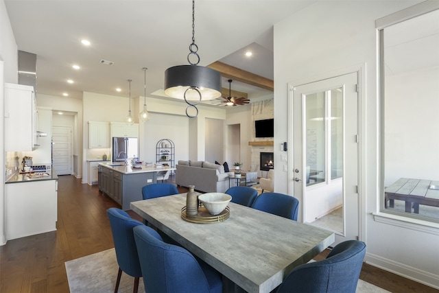 dining room with ceiling fan, dark wood finished floors, a large fireplace, recessed lighting, and visible vents