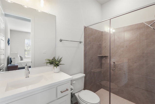 ensuite bathroom featuring vanity, toilet, ensuite bathroom, and a stall shower