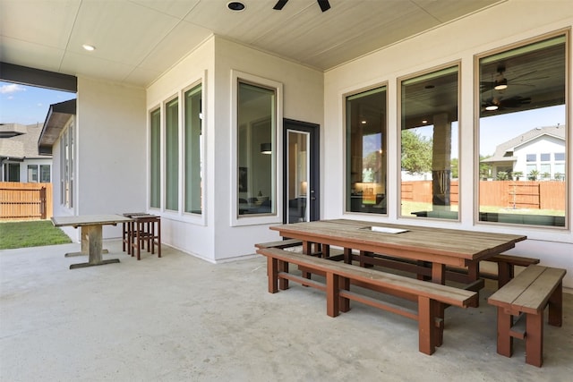 view of patio with outdoor dining area, ceiling fan, and fence