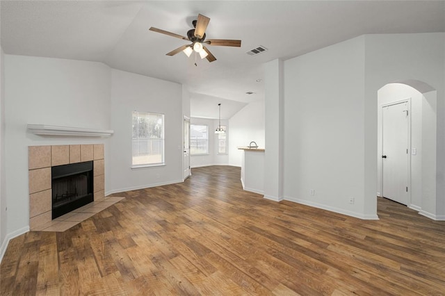 15205 Bullace St, Austin, TX 78724 - unfurnished living room with vaulted ceiling, a ceiling fan, wood finished floors, a tile fireplace, and arched walkways