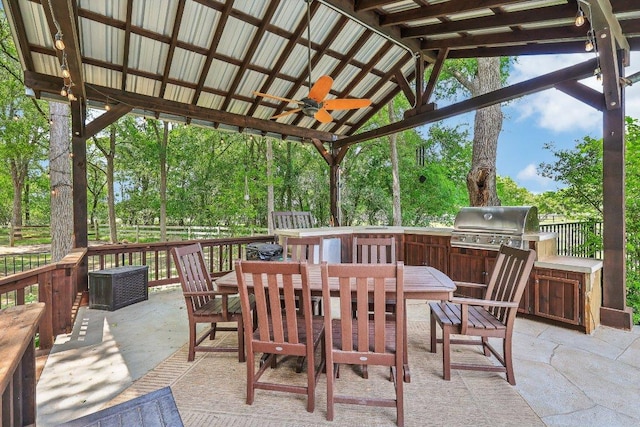 view of patio featuring fence, outdoor dining space, an outdoor kitchen, ceiling fan, and area for grilling