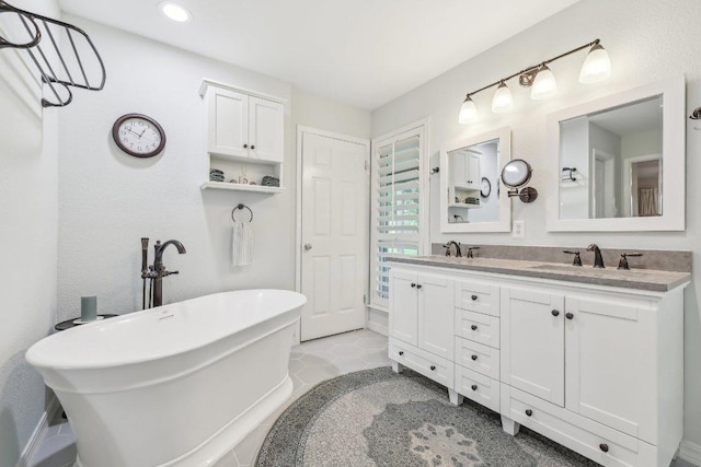 full bath with a sink, a freestanding tub, recessed lighting, and double vanity