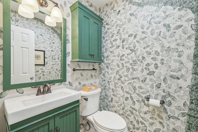 half bathroom with toilet, wallpapered walls, and vanity