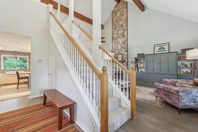 stairway with visible vents, wood finished floors, high vaulted ceiling, and beamed ceiling