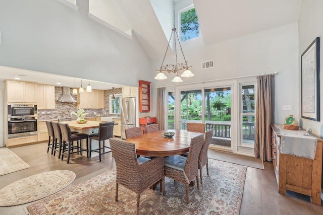 dining area featuring high vaulted ceiling, visible vents, and light wood finished floors