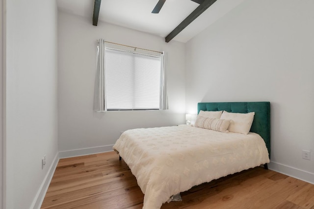 bedroom with baseboards, lofted ceiling with beams, light wood-style flooring, and ceiling fan